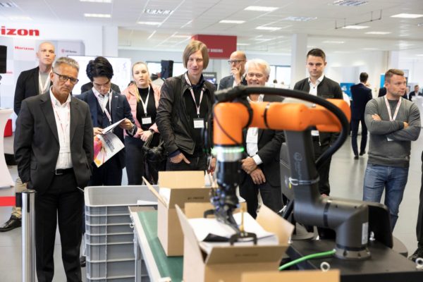 Mithilfe eines Kartonierroboters werden die gehefteten und banderolierten Broschüren in Kartons verpackt. Foto: Horizon GmbH