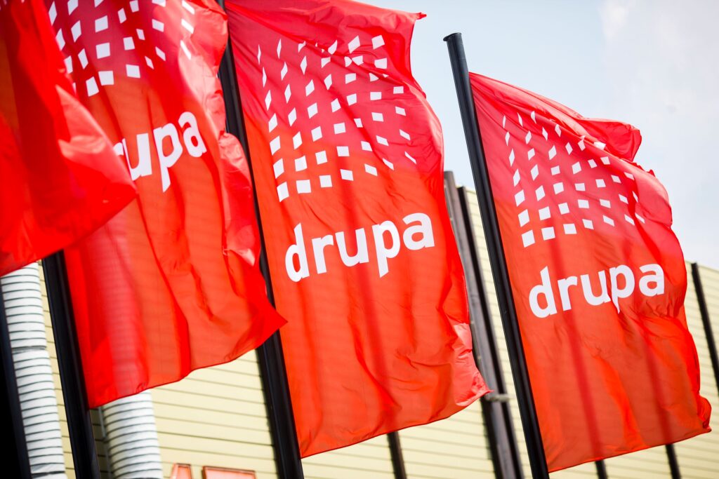 Die wehenden Drupa-Fahnen weisen auf eine hochkarätige internationale Veranstaltung hin. Foto: Messe Düsseldorf/Constanze Tillmann