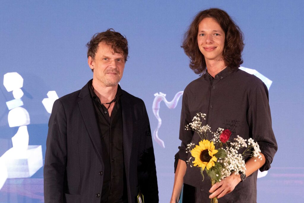 Prof. Tilo Baumgärtel, Prorektor für Lehre und Studium im Fachbereich Kunst, überreichte den DAAD-Preis 2024 an den Buchkunst-Studenten Florian Wagner (r.). Foto: Michel Klehm