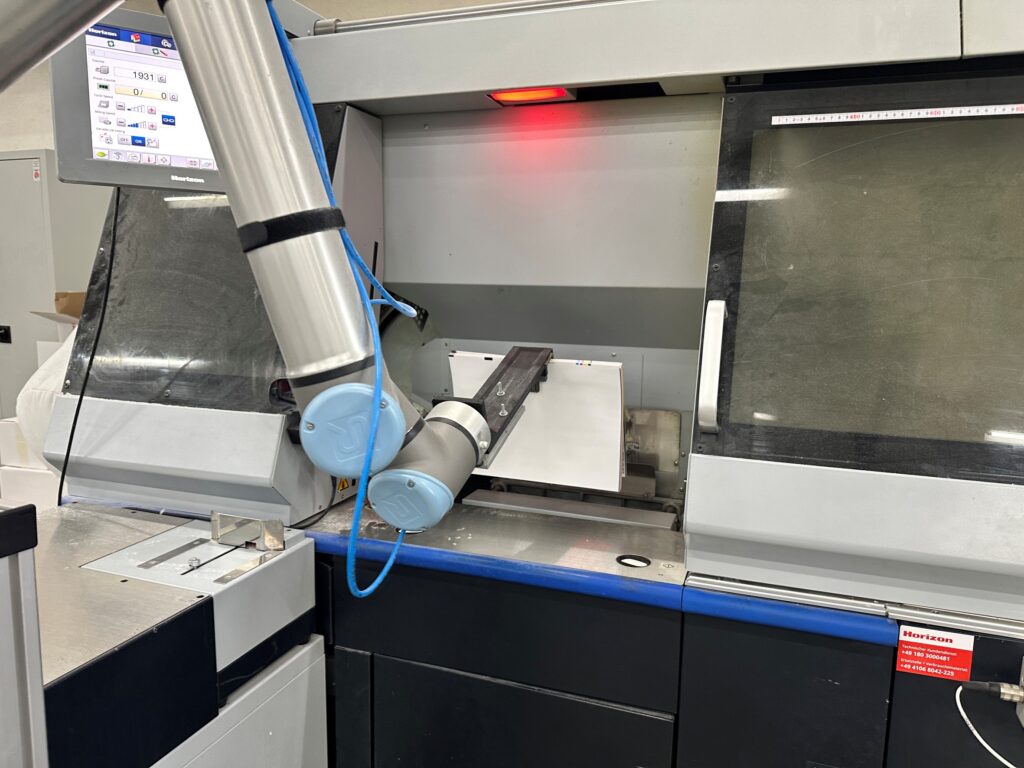Buchblocks werden bei Schimek ganz komfortabel per Roboterarm zugeführt. Foto: Horizon